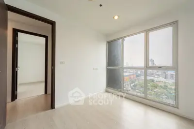 Bright empty room with large window and city view, perfect for customization.