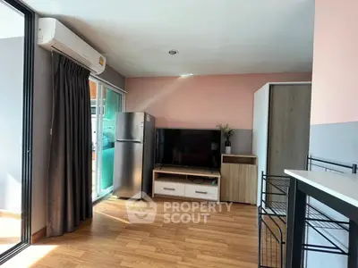 Modern living room with wooden flooring, TV, and balcony access