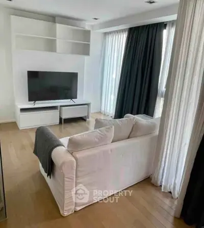 Modern living room with sleek TV setup and cozy white sofa, featuring elegant floor-to-ceiling curtains.