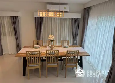 Elegant dining room with wooden table and chairs, surrounded by sheer curtains and modern lighting.