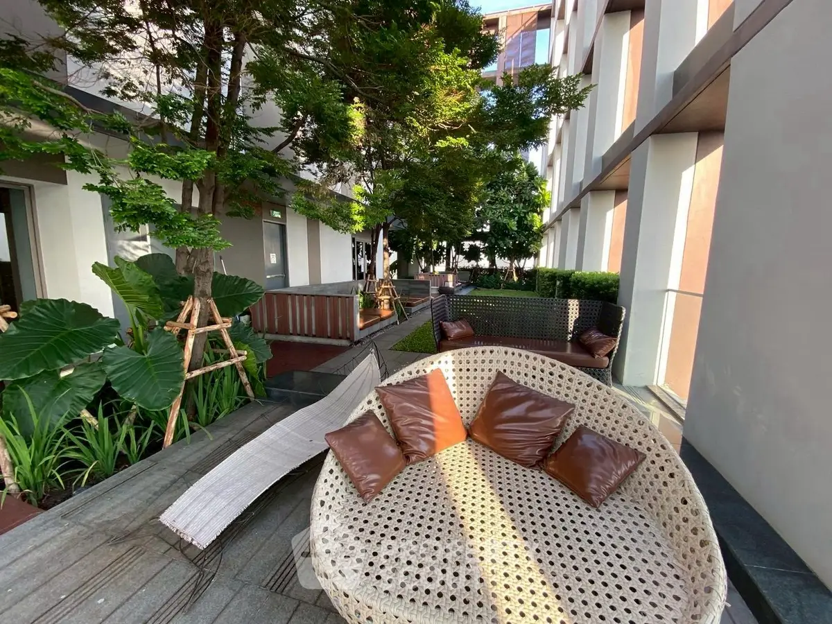 Chic outdoor seating area with modern wicker furniture and lush greenery in a stylish residential complex.
