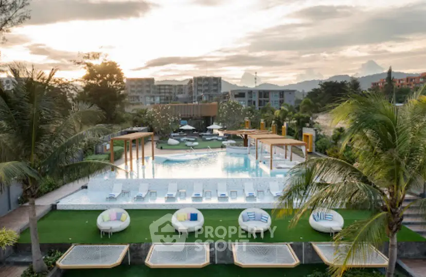 Luxurious resort-style pool with modern sun loungers and lush landscaping at sunset.