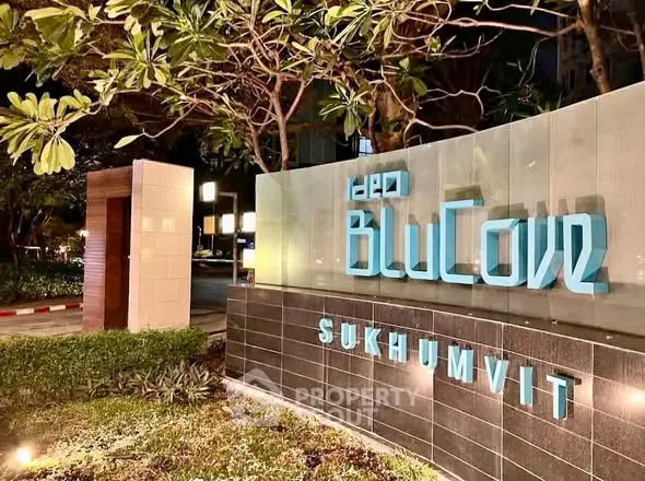 Modern entrance sign of luxury condo BluCove Sukhumvit with lush greenery and ambient lighting.
