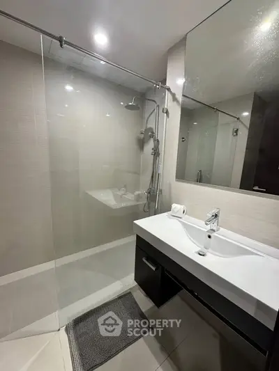 Modern bathroom with glass shower and sleek vanity in contemporary apartment.