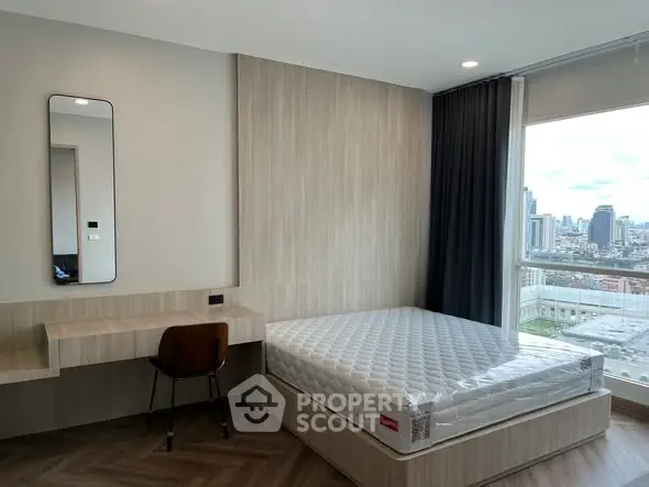 Modern bedroom with city view, featuring a sleek desk and comfortable bed.