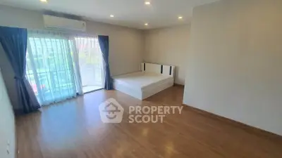 Spacious bedroom with large windows and wooden flooring in modern apartment