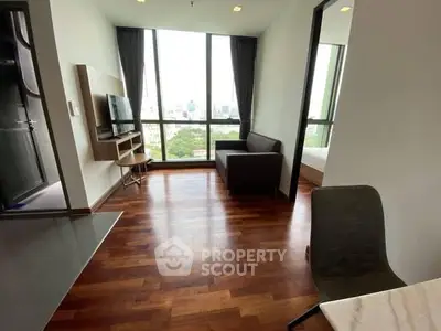 Modern living room with hardwood floors and city view, featuring a cozy sofa and wall-mounted TV.