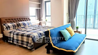 Spacious modern bedroom with stylish decor and large windows leading to a balcony.