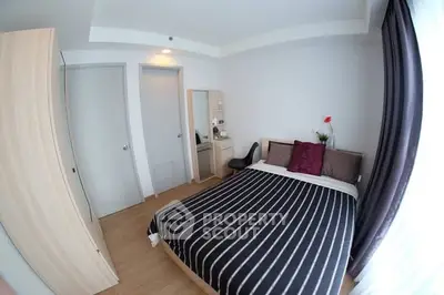 Cozy bedroom with modern decor and ample natural light, featuring a stylish striped bedspread and elegant furnishings.