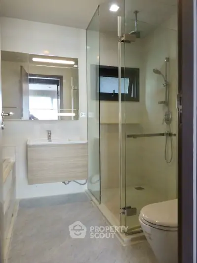 Modern bathroom with glass shower and sleek fixtures in contemporary apartment.