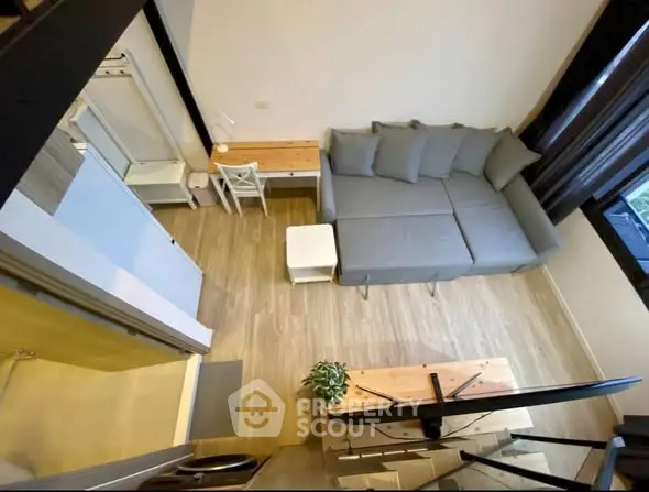 Modern living room with stylish gray sofa and wooden flooring, featuring a cozy workspace.