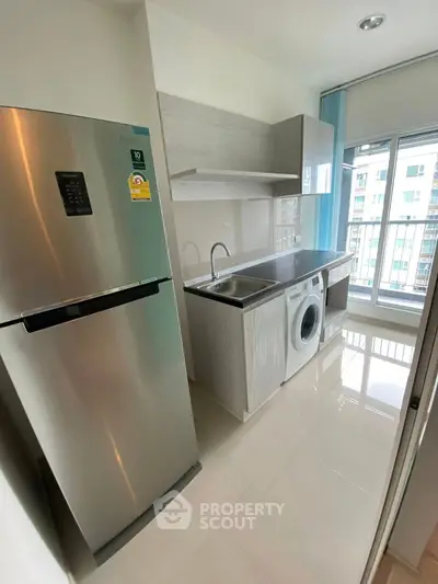 Modern kitchen with stainless steel fridge and washing machine in bright apartment