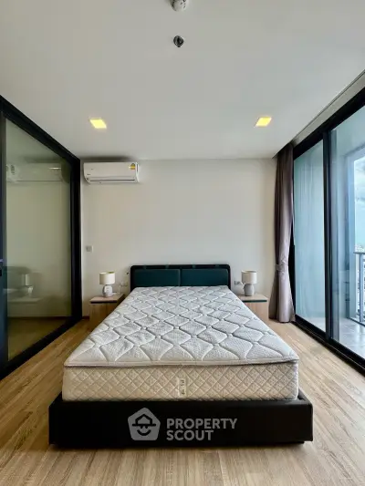Modern bedroom with large windows and balcony access in a stylish apartment.