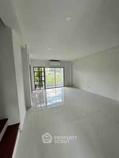Spacious living room with large windows and glossy tiled floors, offering a bright and airy atmosphere.