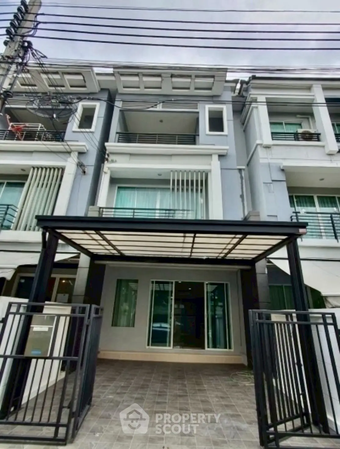 Modern multi-story townhouse with gated entrance and covered parking area.