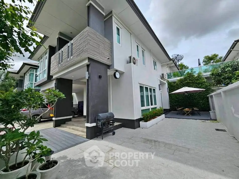 Modern two-story house with spacious driveway and outdoor seating area.