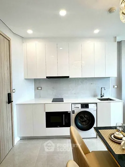 Modern kitchen with sleek white cabinets, built-in appliances, and elegant dining setup.