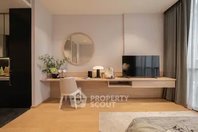 Modern living room with stylish decor, featuring a TV, round mirror, and elegant furniture.