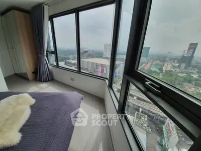Stunning bedroom with panoramic city view and large windows in modern high-rise apartment.