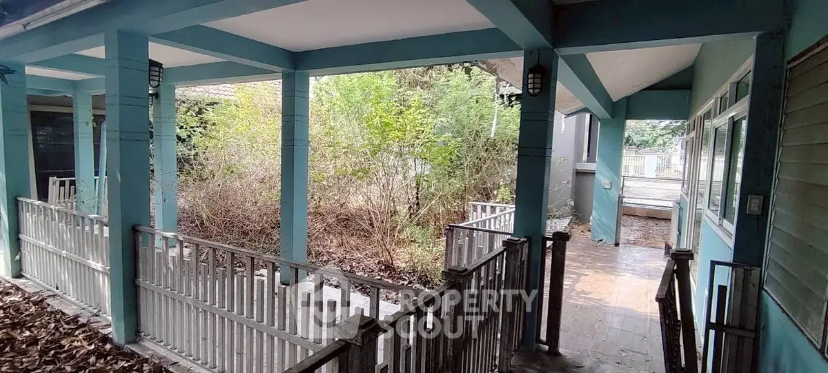 Charming fixer-upper with spacious porch and lush greenery, perfect for renovation enthusiasts.