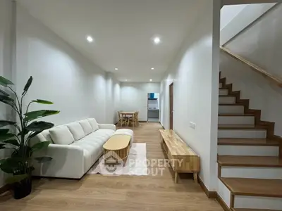 Modern living room with cozy sofa, wooden flooring, and staircase in a stylish home interior.