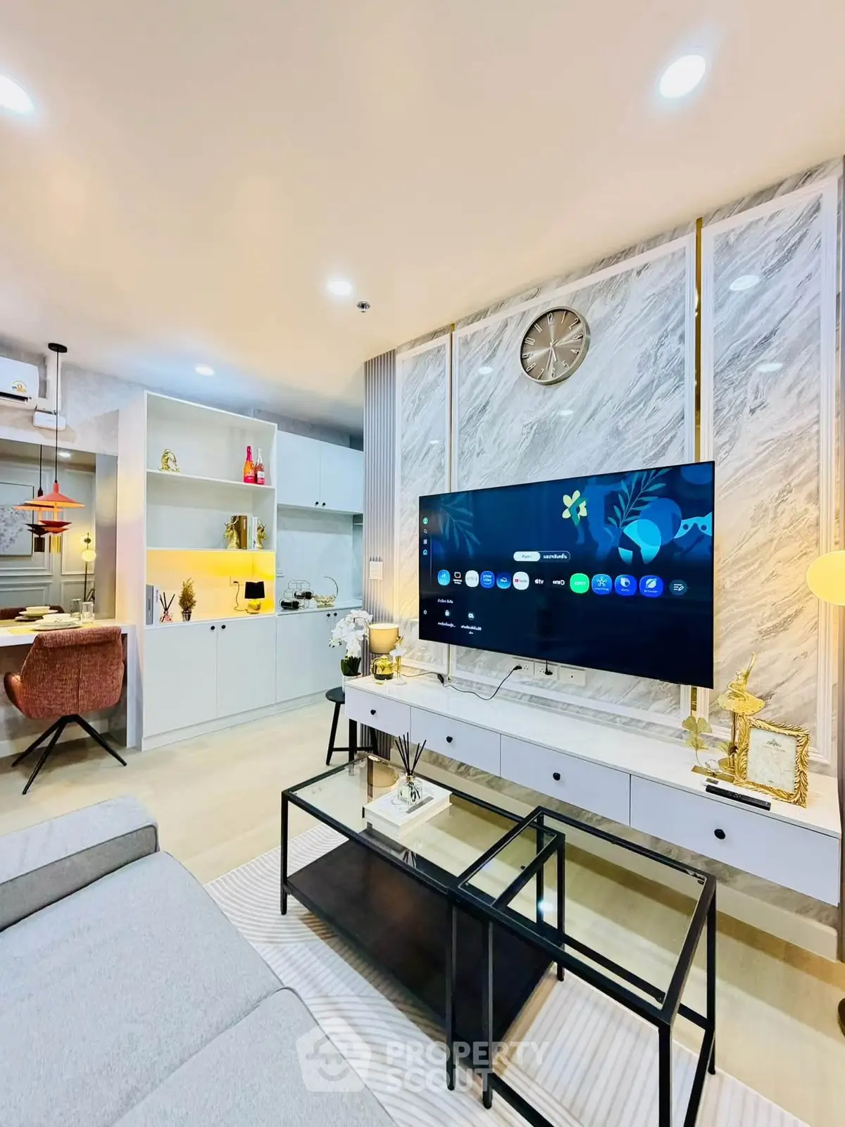 Modern living room with stylish decor and open kitchen layout, featuring a wall-mounted TV and elegant lighting.