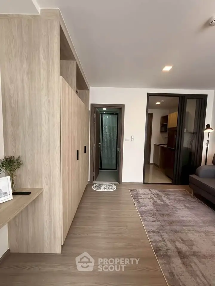Modern living room with wooden flooring and open kitchen layout, featuring sleek design and cozy ambiance.