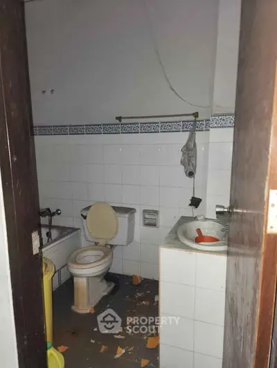 Fixer-upper bathroom with broken tiles and basic fixtures, ideal for renovation.