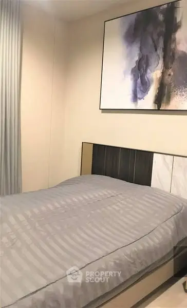 Modern bedroom with stylish decor and abstract art on the wall.