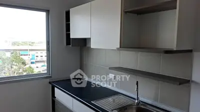 Modern kitchen with sleek cabinetry and large window view.