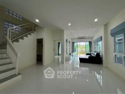Spacious modern living room with large windows and sleek staircase