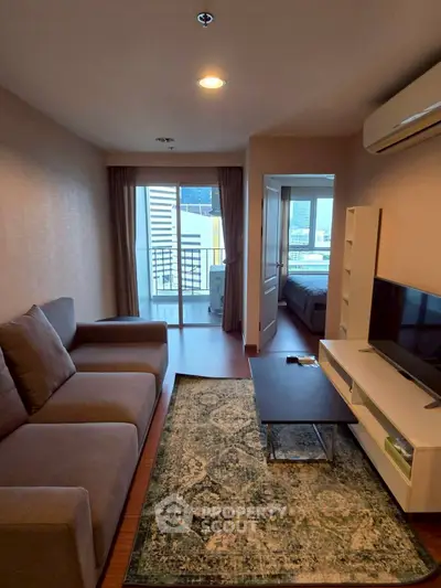 Modern living room with balcony view, cozy sofa, and sleek TV setup in urban apartment.