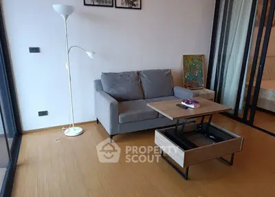 Modern living room with stylish furniture and wooden flooring, featuring a cozy gray sofa and a unique lift-top coffee table.