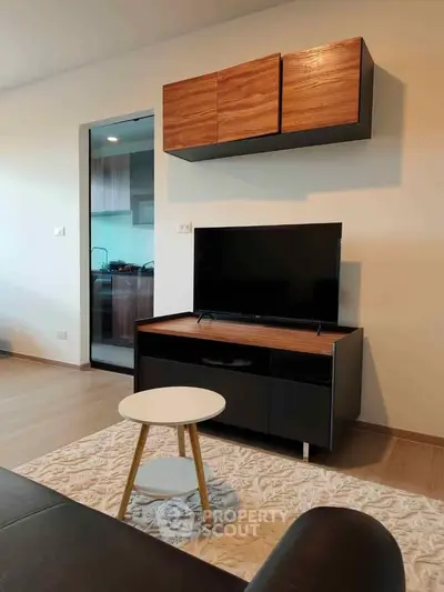 Modern living room with sleek TV stand and wall-mounted cabinet, open view to stylish kitchen.