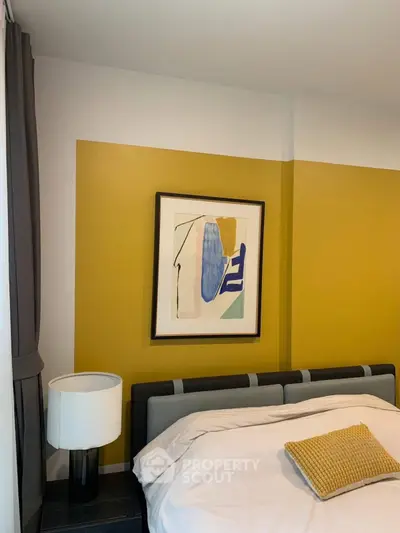 Modern bedroom with stylish decor and abstract art on mustard accent wall.