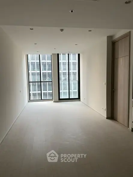 Spacious modern living room with large windows and natural light in a high-rise building.
