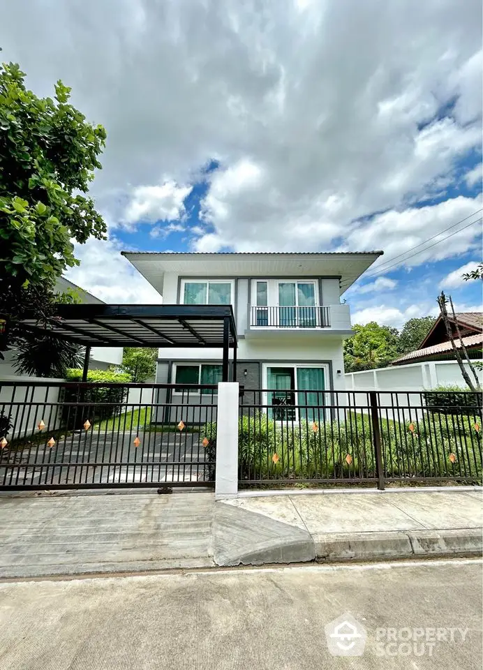 Modern two-story house with balcony and gated entrance in a serene neighborhood.