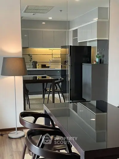 Modern kitchen with sleek cabinetry and dining area, featuring elegant lighting and contemporary design.
