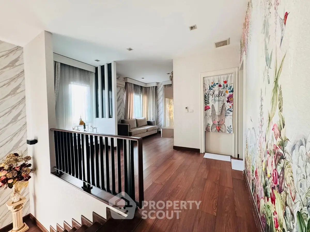 Charming interior with elegant wooden flooring and floral wall art, featuring a cozy seating area and natural light.