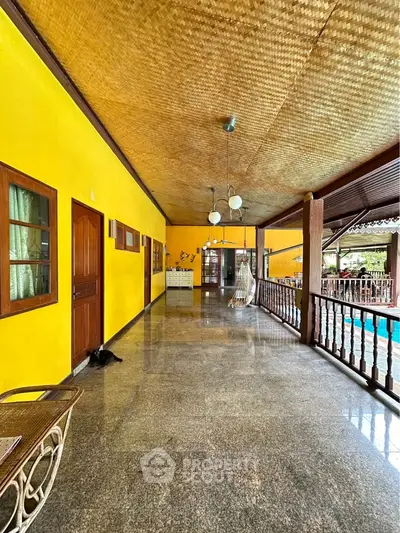 Spacious outdoor corridor with vibrant yellow walls and pool view, perfect for relaxation.