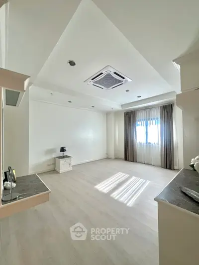 Spacious and bright living room with modern ceiling design and large window.
