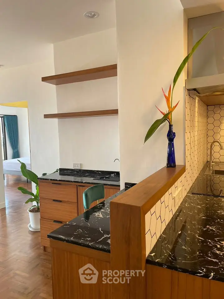 Stylish kitchen with marble countertops and open shelving, adjacent to a cozy bedroom.