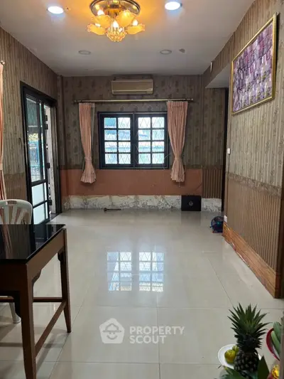 Spacious living room with elegant chandelier and large windows, perfect for natural light.