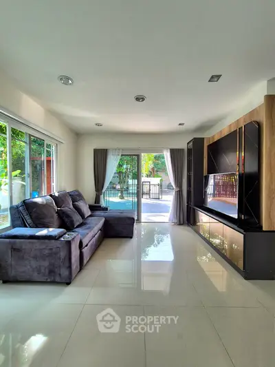Spacious living room with modern decor and large windows overlooking a lush garden.