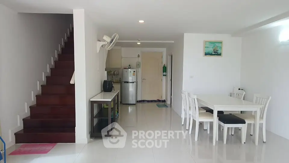 Spacious open-plan living area with dining table and modern kitchen in bright home.