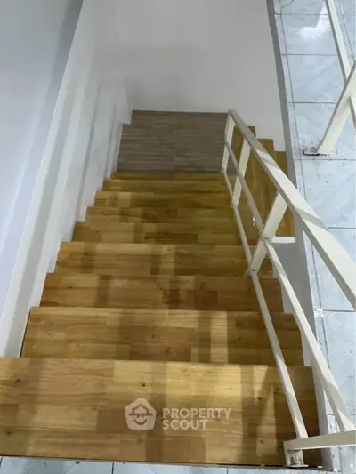 Modern wooden staircase with sleek white railing in a contemporary home interior.