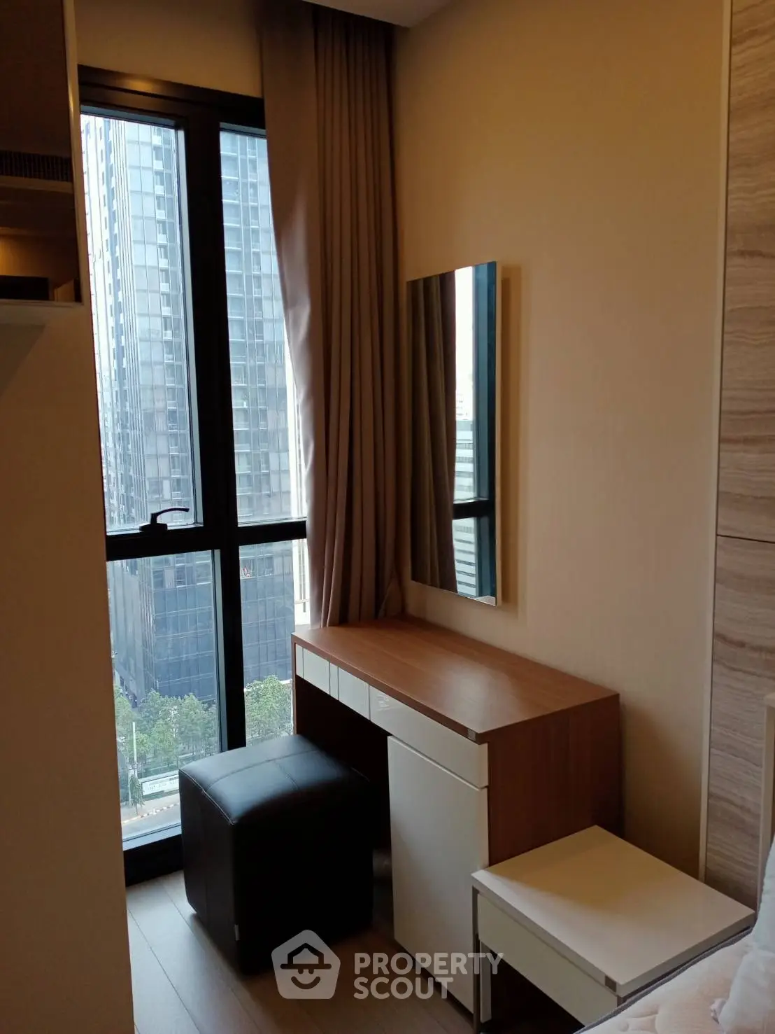 Modern bedroom with city view, featuring a sleek vanity and floor-to-ceiling windows.