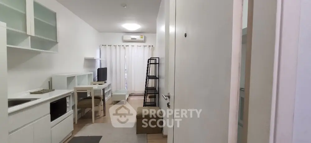 Modern compact living room with minimalist furniture and built-in kitchen area.