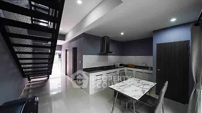 Modern kitchen with sleek design and open layout under a stylish staircase.