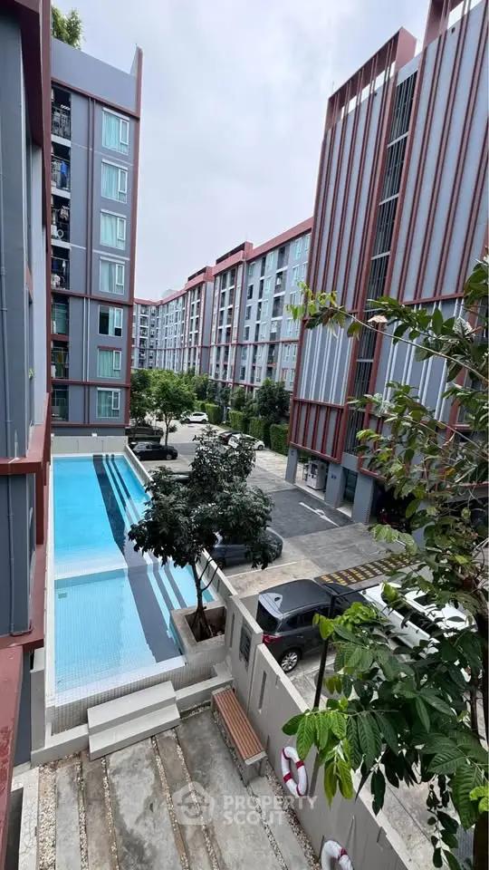 Modern apartment complex with pool and parking area, showcasing urban living.